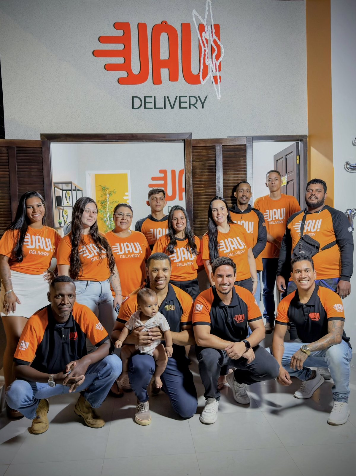 Equipe do Uau! Delivery reunida em frente à sede, de uniforme laranja