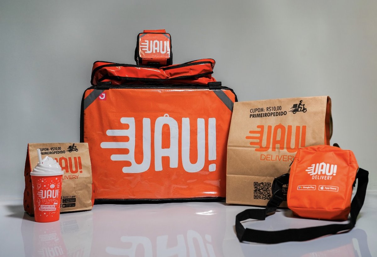 Materiais da marca Uau! Delivery: bag térmica grande, mini bag, sacolas de papel com o cupom impresso, copo e bolsa, todos em laranja